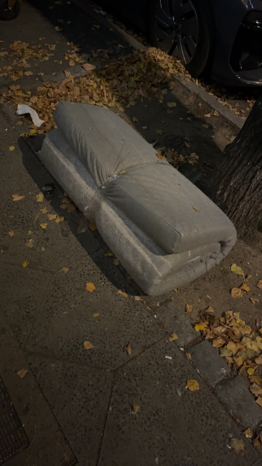 Eine Matratze liegt auf dem Gehweg neben herbstlichem Laub und parkenden Fahrzeugen, Hermannstraße 139, Neukölln